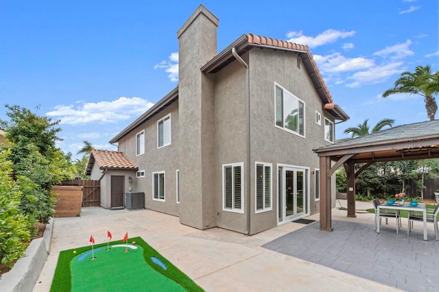 rear view of house with a gazebo, a chimney, a patio area, and stucco siding