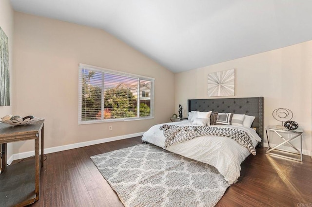bedroom featuring baseboards, wood finished floors, and vaulted ceiling