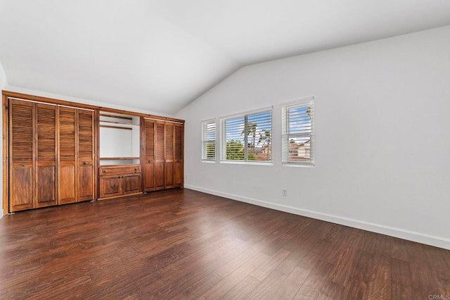 unfurnished bedroom with dark wood-style flooring, baseboards, and lofted ceiling