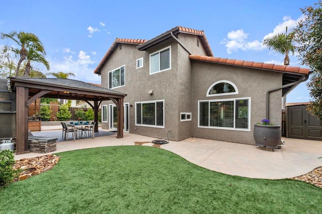 back of property featuring a lawn, a shed, a patio area, a gazebo, and an outbuilding