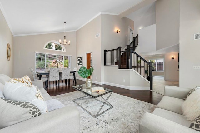 living area featuring a notable chandelier, high vaulted ceiling, wood finished floors, ornamental molding, and stairway