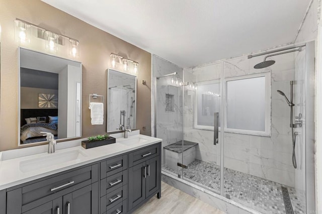 full bath with double vanity, a marble finish shower, a sink, and ensuite bathroom