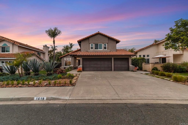 mediterranean / spanish home with a tile roof, a garage, fence, concrete driveway, and stucco siding