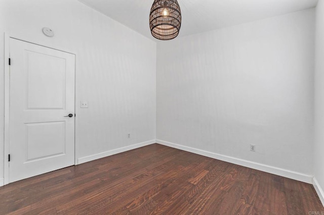 unfurnished room with baseboards and dark wood finished floors