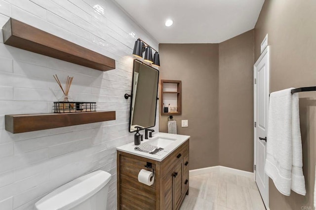 half bath with vanity, marble finish floor, baseboards, and toilet