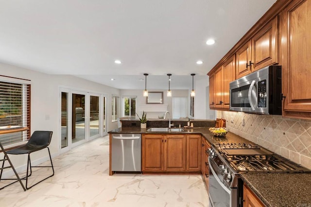 kitchen with a sink, brown cabinets, stainless steel appliances, and a peninsula