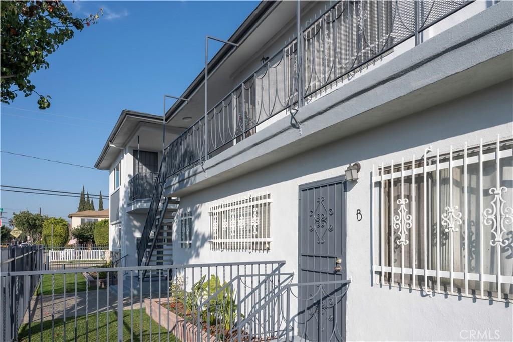 view of side of home with stucco siding, fence, and stairway