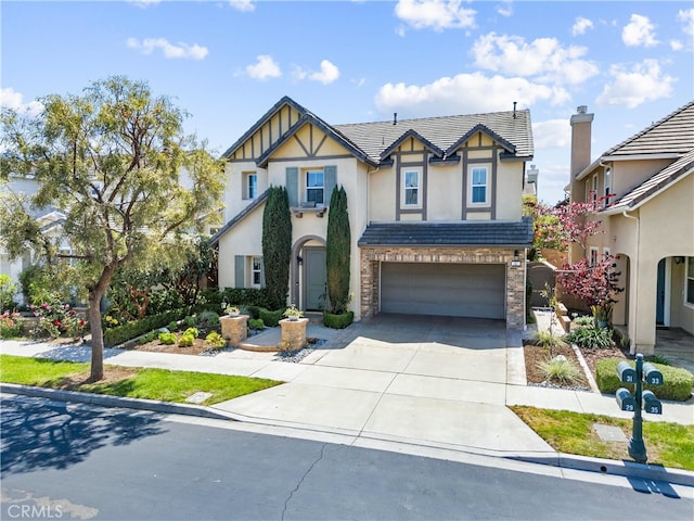 tudor house featuring an attached garage, a tiled roof, stucco siding, and concrete driveway