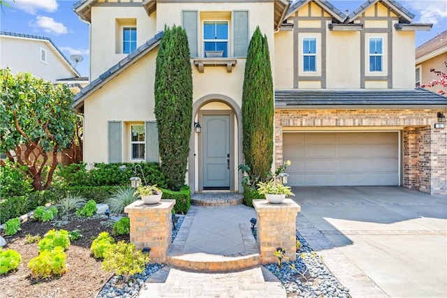 view of front facade with stucco siding, an attached garage, driveway, and brick siding