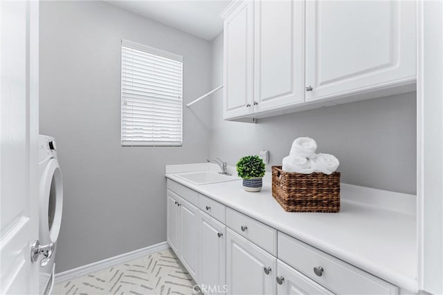 laundry area with baseboards, cabinet space, washer / dryer, and a sink