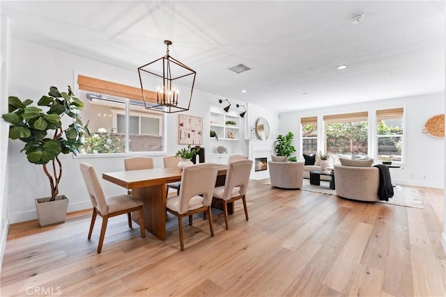 dining area featuring baseboards, a notable chandelier, light wood-style floors, and visible vents