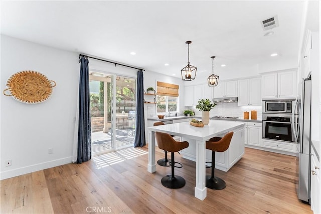 kitchen with white cabinets, under cabinet range hood, stainless steel appliances, and recessed lighting
