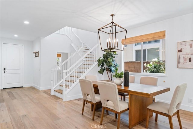 dining area featuring light wood-style floors, stairway, and an inviting chandelier