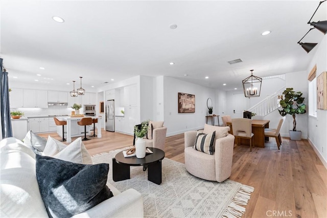living area featuring recessed lighting, visible vents, light wood-style flooring, stairs, and a notable chandelier