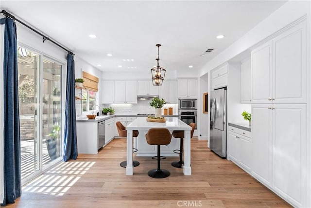 kitchen featuring stainless steel appliances, backsplash, white cabinetry, and a healthy amount of sunlight