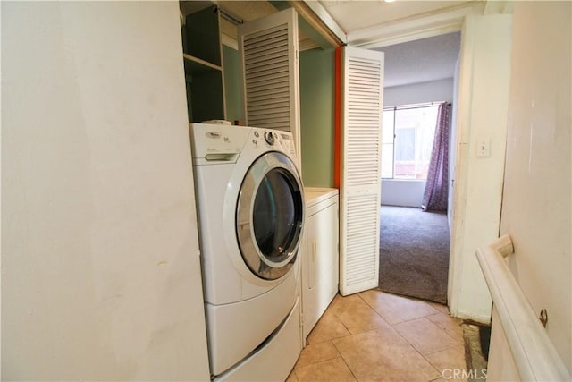 washroom featuring washer and dryer, laundry area, light tile patterned floors, and light carpet