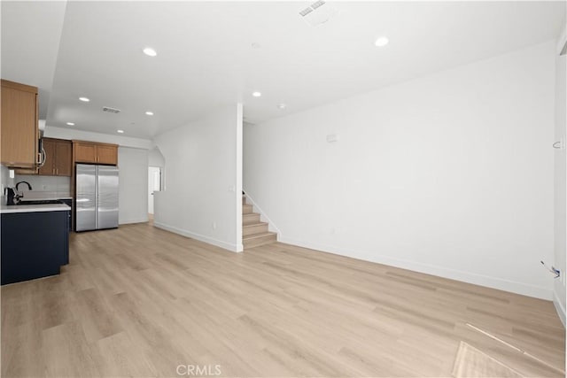 kitchen featuring stainless steel refrigerator, light countertops, open floor plan, light wood-style floors, and recessed lighting