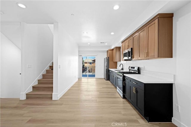 kitchen with light countertops, recessed lighting, stainless steel appliances, a sink, and light wood-style flooring