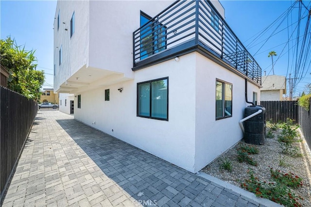 view of side of home with a fenced backyard, stucco siding, and a patio