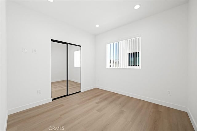 unfurnished bedroom with recessed lighting, a closet, baseboards, and light wood-type flooring
