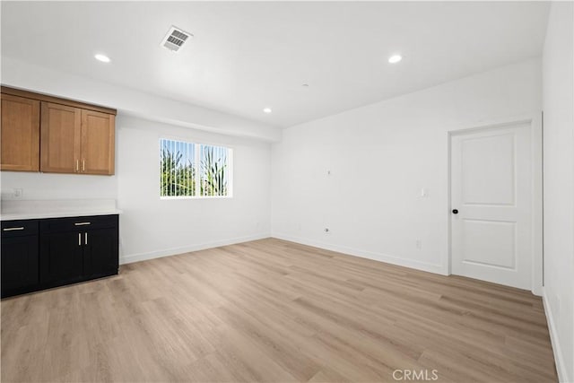 interior space featuring baseboards, visible vents, recessed lighting, and light wood finished floors
