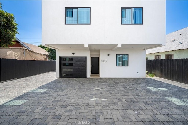 exterior space featuring stucco siding, fence, a patio area, and decorative driveway