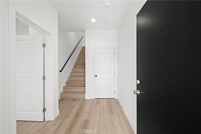 hallway with baseboards, stairs, recessed lighting, and light wood finished floors