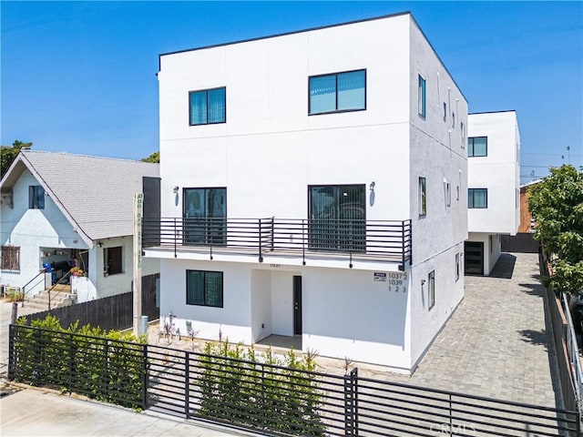 view of front of house featuring a fenced front yard, a balcony, and stucco siding