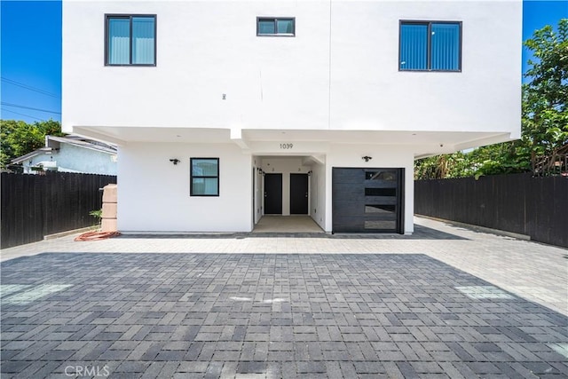 exterior space with decorative driveway, fence, and stucco siding