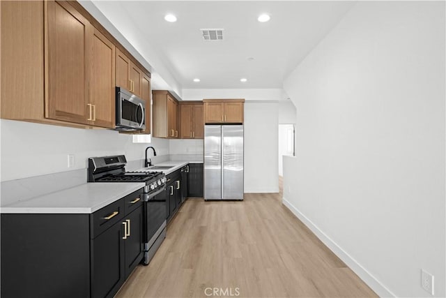 kitchen featuring light countertops, a sink, stainless steel appliances, visible vents, and light wood-style floors