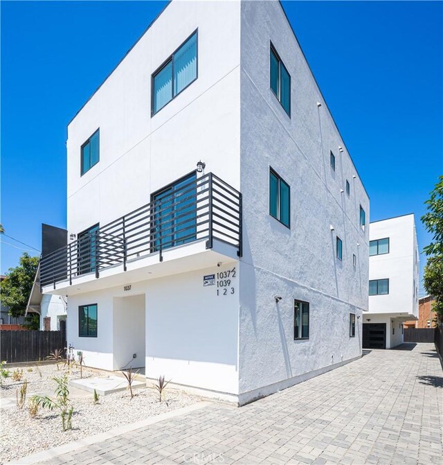 rear view of property with stucco siding and fence