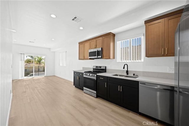 kitchen with light countertops, visible vents, light wood-style flooring, stainless steel appliances, and a sink