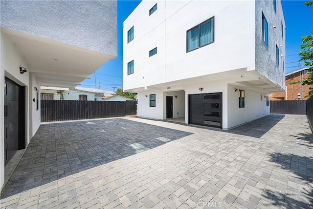 back of house with a patio area, stucco siding, fence, decorative driveway, and a garage
