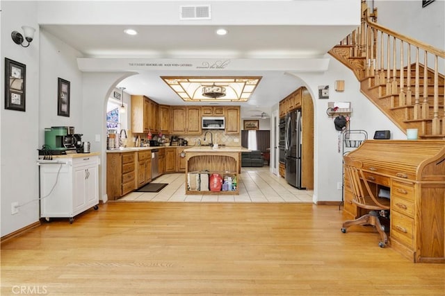 interior space with visible vents, stainless steel appliances, light wood-style floors, and arched walkways