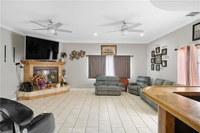 living room with ornamental molding, recessed lighting, a ceiling fan, and a glass covered fireplace