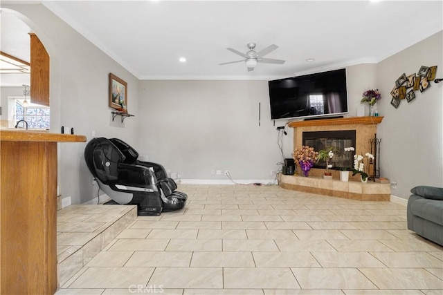 living area featuring a tiled fireplace, recessed lighting, arched walkways, ornamental molding, and a ceiling fan
