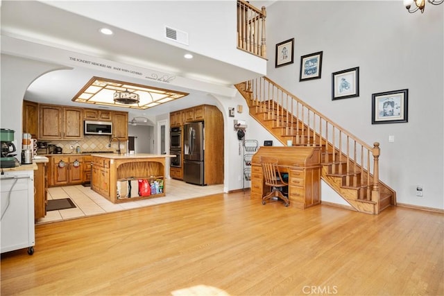 unfurnished living room featuring visible vents, arched walkways, stairs, and light wood finished floors
