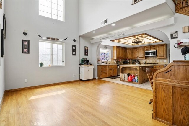 interior space featuring visible vents, a healthy amount of sunlight, light wood-style floors, and arched walkways