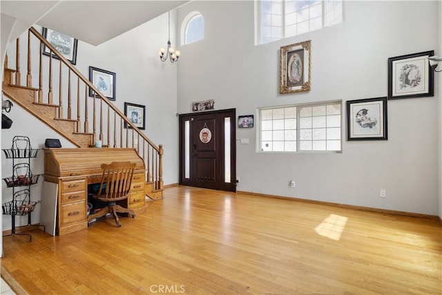 foyer entrance featuring a towering ceiling, wood finished floors, and a healthy amount of sunlight