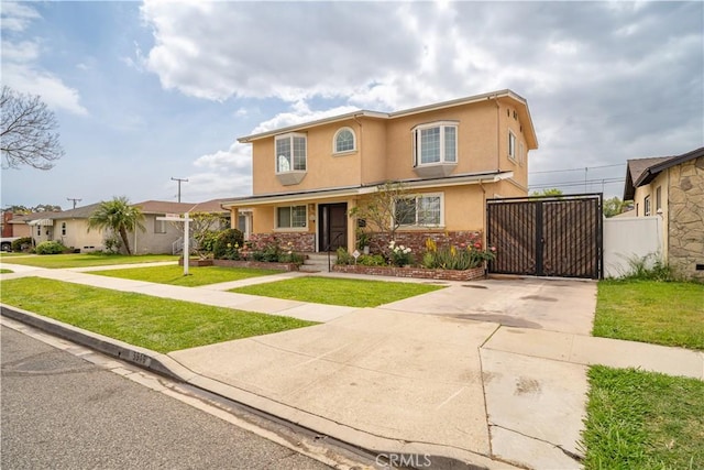 traditional home featuring stucco siding, a gate, fence, driveway, and a front yard