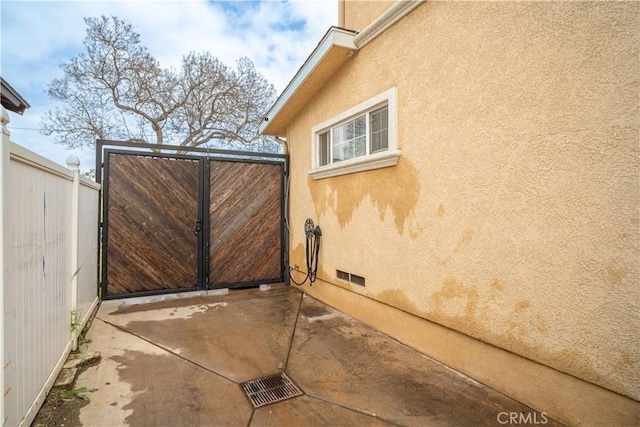 view of gate with fence and a patio