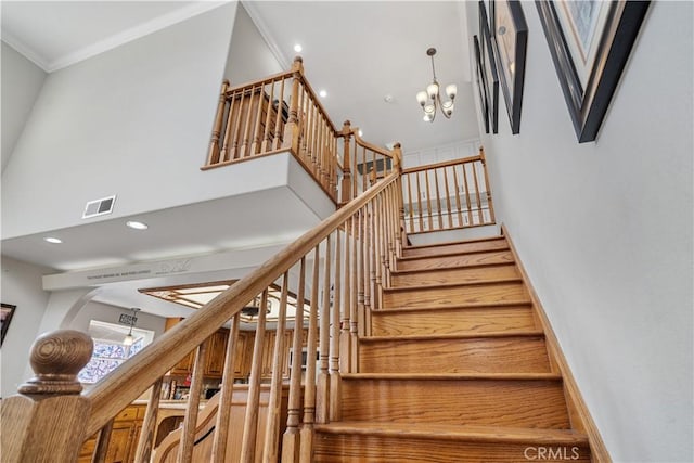 stairs featuring crown molding, visible vents, an inviting chandelier, recessed lighting, and a high ceiling