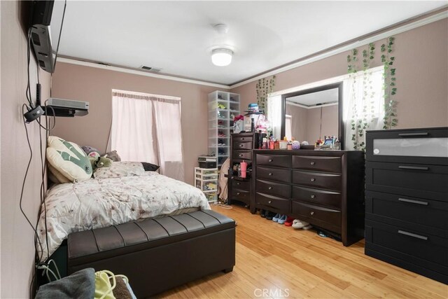 bedroom with visible vents, wood finished floors, and ornamental molding