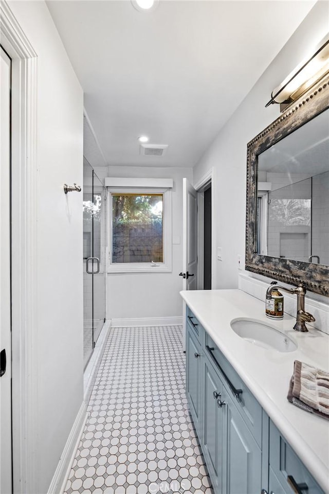 bathroom with vanity, baseboards, a stall shower, and visible vents