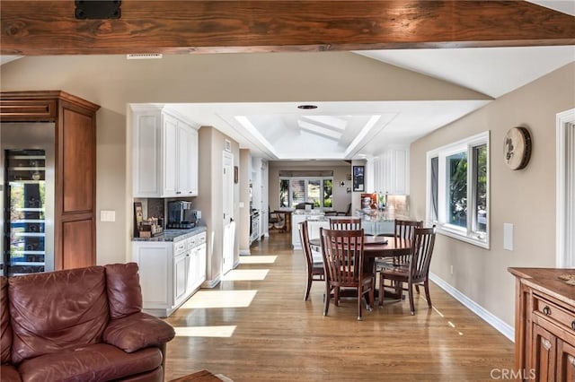 dining room featuring baseboards, lofted ceiling with beams, wood finished floors, and a tray ceiling