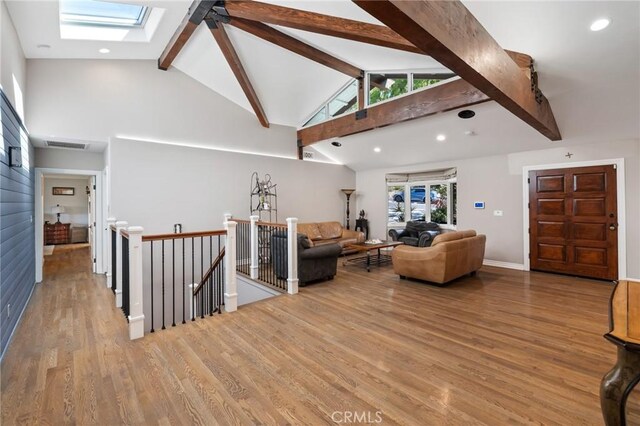 living room featuring a skylight, beam ceiling, wood finished floors, high vaulted ceiling, and recessed lighting