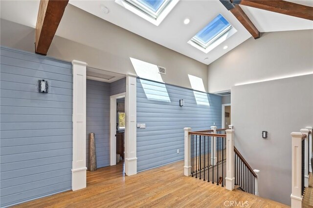 interior space with an upstairs landing, a healthy amount of sunlight, wood finished floors, and lofted ceiling with skylight