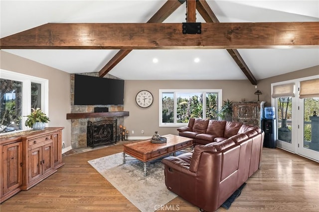 living room with baseboards, a stone fireplace, vaulted ceiling with beams, recessed lighting, and light wood-type flooring