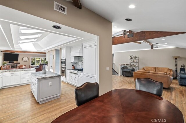 kitchen with visible vents, white cabinets, custom exhaust hood, open floor plan, and stainless steel appliances
