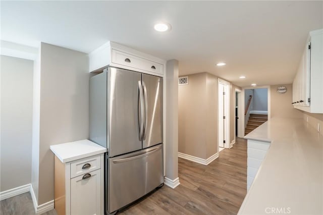 kitchen featuring white cabinets, light countertops, freestanding refrigerator, recessed lighting, and baseboards